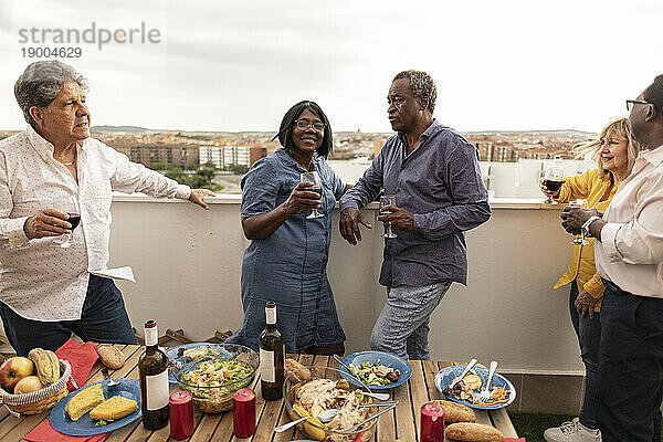 Ältere Freunde genießen Essen und Getränke auf dem Balkon