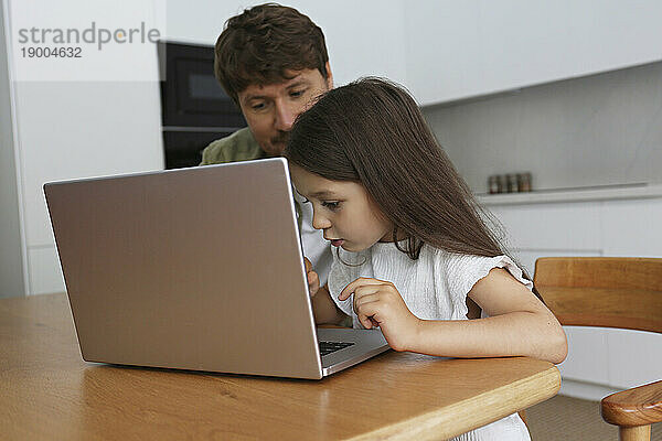 Mädchen lernt mit Vater zu Hause  Laptop zu benutzen