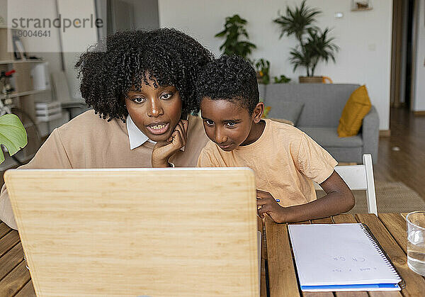 Mutter unterrichtet Sohn am Laptop im heimischen Wohnzimmer