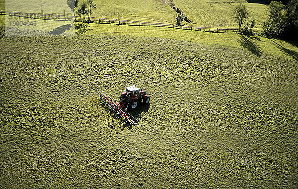 Mann mäht Land mit Traktor an sonnigem Tag