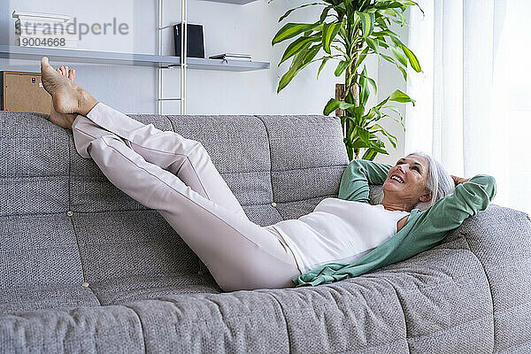 Glückliche Frau entspannt sich zu Hause auf dem Sofa