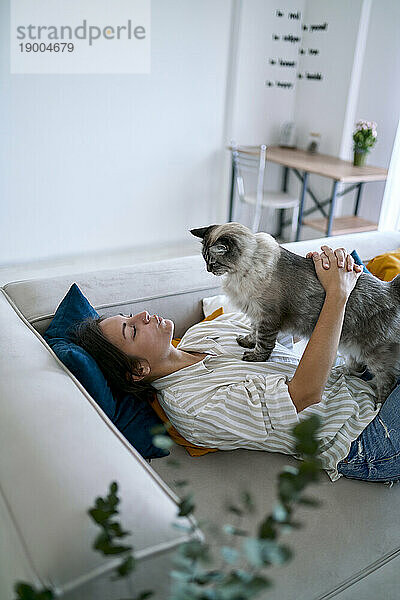 Frau streichelt Katze auf Sofa zu Hause