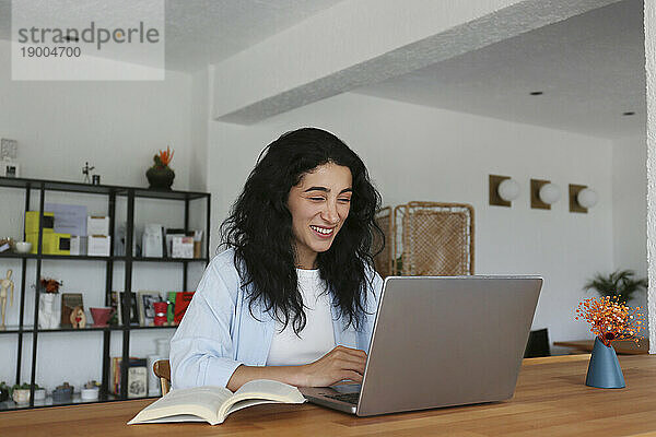 Lächelnde Frau lernt mit Laptop im Café