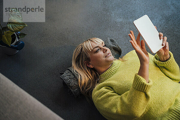 Frau liegt auf dem Boden und benutzt zu Hause einen Tablet-PC