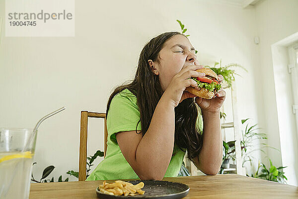 Hungriges Mädchen  das zu Hause Burger isst