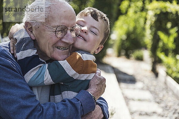 Glücklicher Junge umarmt Großvater im Hinterhof