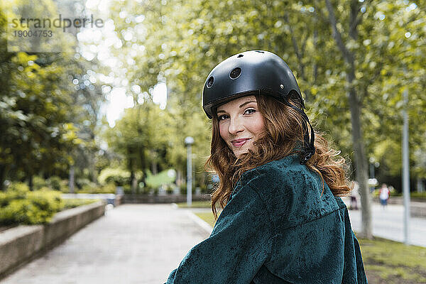 Lächelnde junge Frau mit Helm im Park