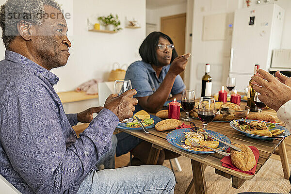 Ältere Männer und Frauen unterhalten sich mit Freunden am Esstisch
