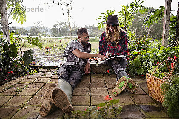 Junges Paar mit Tagebuch sitzt im Garten
