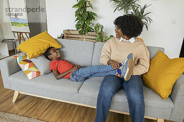 Glückliche Mutter mit Sohn  der zu Hause auf dem Sofa liegt