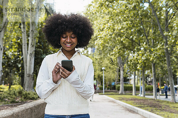 Glückliche Afro-Frau benutzt Smartphone im Park