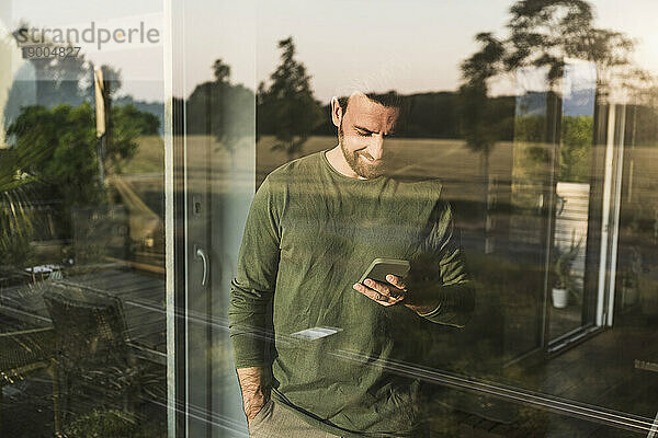 Mann benutzt Smartphone  gesehen durch Glas