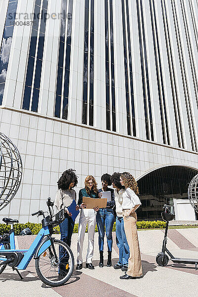 Geschäftsfrauen stehen an einem sonnigen Tag gemeinsam vor dem Gebäude
