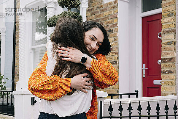 Frau umarmt Freund vor Haus
