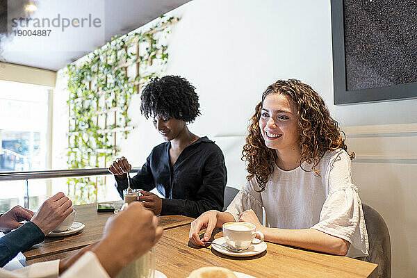 Glückliche junge Frau verbringt Zeit mit Freunden im Café