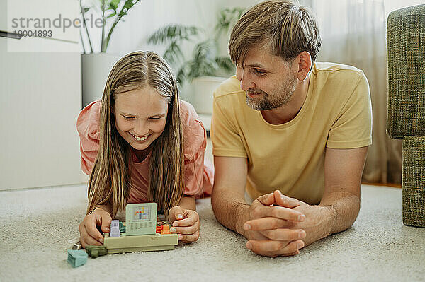 Lächelnder Vater und Tochter spielen zu Hause