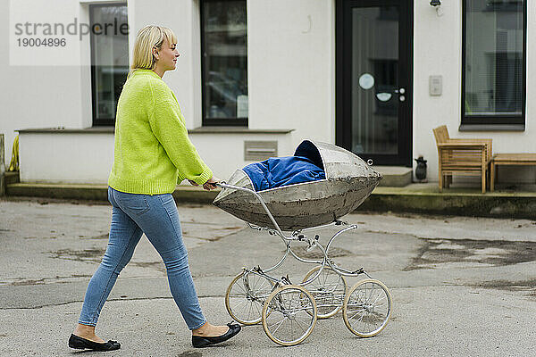 Frau läuft mit Kinderwagen auf der Straße