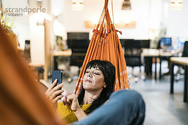 Geschäftsfrau entspannt sich und nutzt Smartphone im Büro
