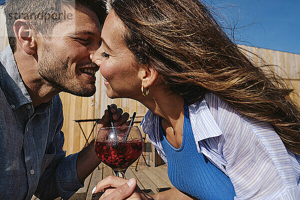 Romantisches Paar küsst sich auf einem Tisch am Strand