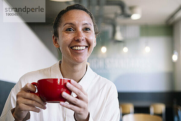 Lächelnde Geschäftsfrau hält Kaffeetasse im Café