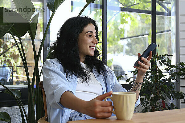 Lächelnde Frau hält Smartphone im Café