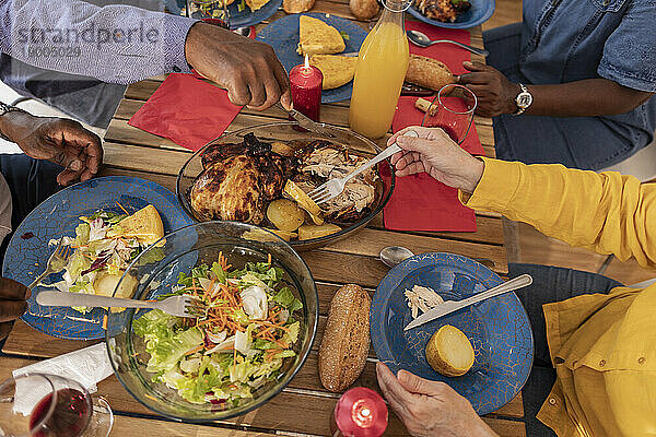 Multikulturelle ältere Freunde genießen Essen und Getränke am Esstisch zu Hause