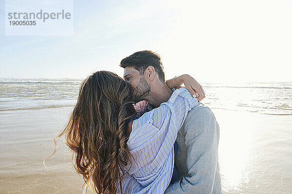 Romantisches Paar umarmt und küsst sich am Strand