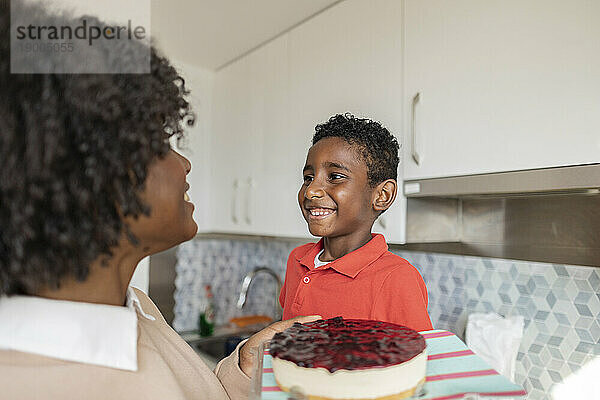 Glückliche Mutter und Sohn mit Kuchen in der heimischen Küche