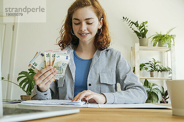 Glückliche junge Frau mit Währung  die Finanzrechnungen berechnet