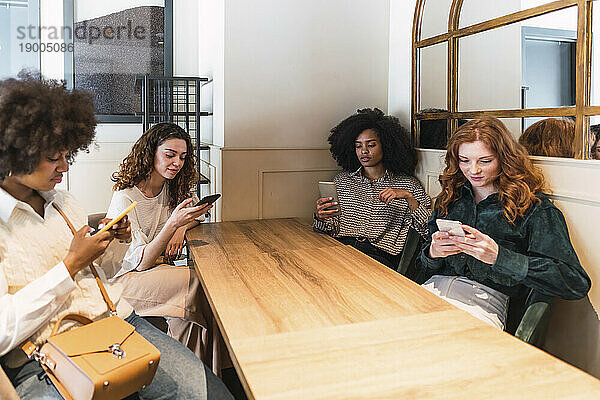 Fröhliche Freunde nutzen gemeinsam ihr Smartphone im Café