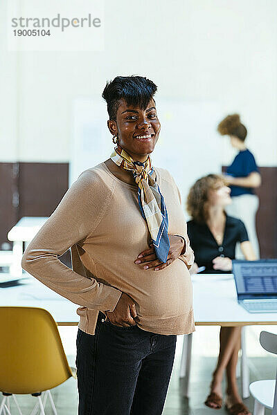 Glückliche schwangere Geschäftsfrau  die im Büro steht