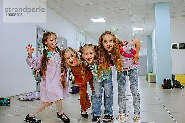 Joyful school girls standing near entrance hallway