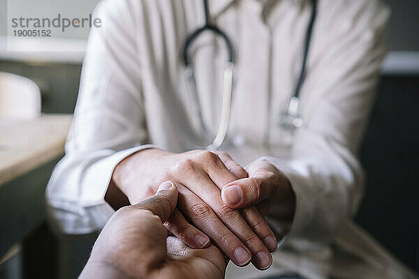 Arzt hält die Hand des Patienten in der Klinik