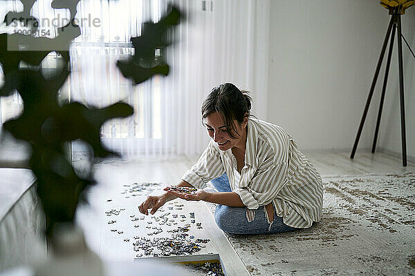 Happy woman playing puzzle in living room at home