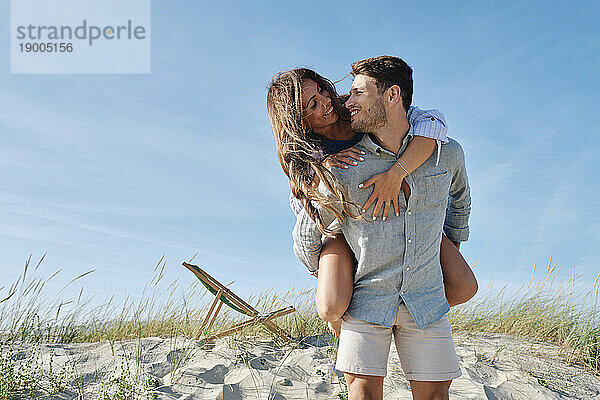 Romantic man piggybacking girlfriend at beach