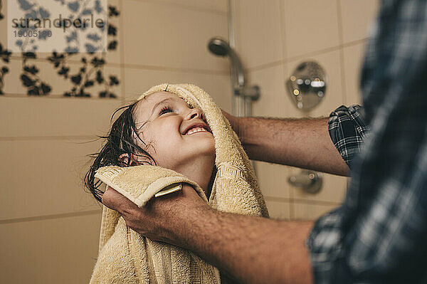 Vater wischt glücklichen Sohn mit Handtuch im Badezimmer ab