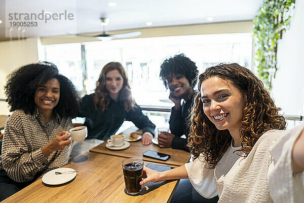 Glückliche Frau macht Selfie mit Freunden und genießt es im Café