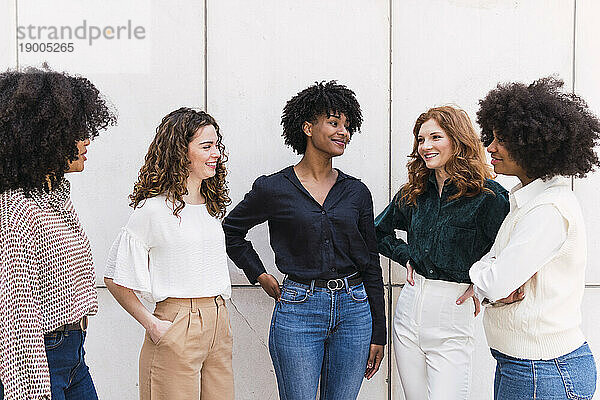 Lächelnde Geschäftsfrauen verbringen gemeinsam Zeit vor der Wand