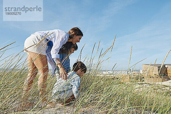 Mutter mit Kindern spielen im Gras am Strand