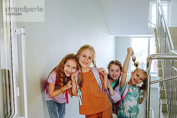 Happy schoolgirls standing at school staircase