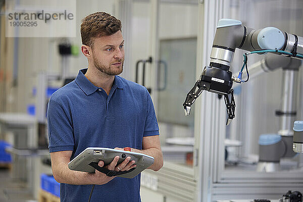 Techniker bedient Roboterarm mit Geräten in der Industrie
