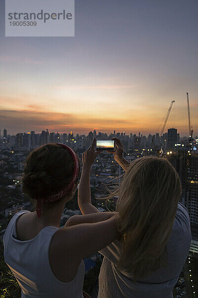 Freunde fotografieren Stadt mit Himmel in der Abenddämmerung