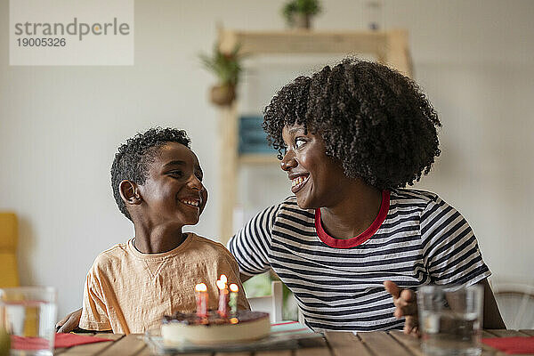 Glückliche Mutter  die zu Hause den Geburtstag ihres Sohnes mit Kuchen feiert