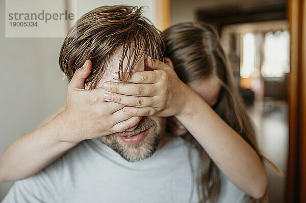 Daughter covering father's eyes with hand