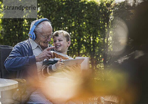 Glücklicher älterer Mann mit kabellosen Kopfhörern  der Spaß mit seinem Enkel hat