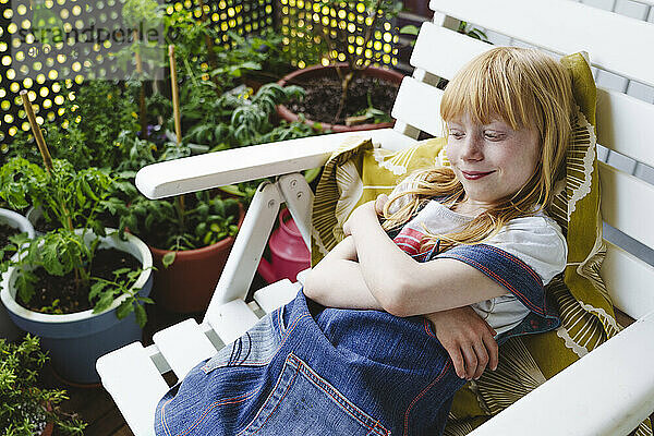 Smiling girl resting on armchair in balcony