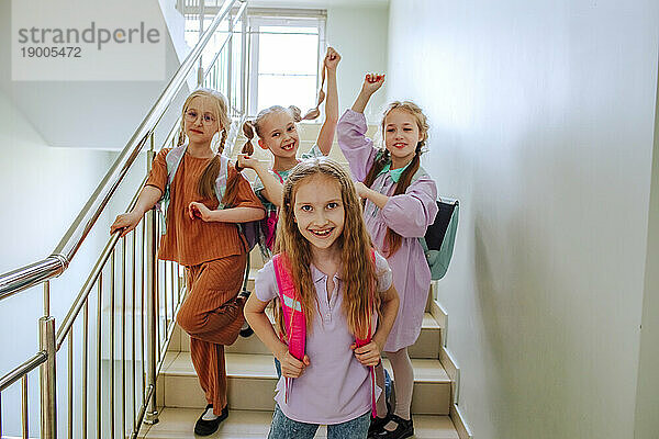 Fröhliche Schulmädchen stehen auf der Schultreppe