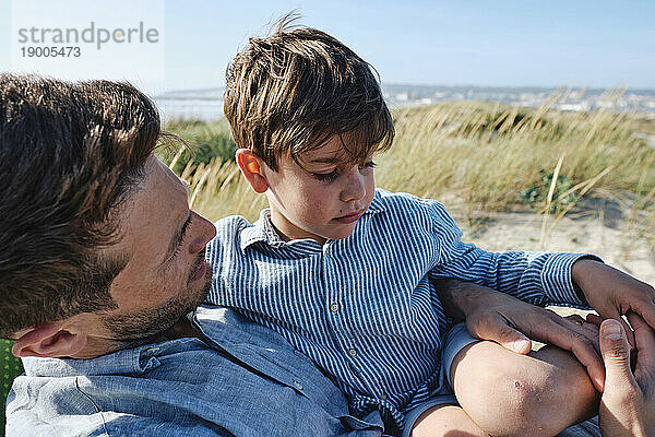Vater trägt Sohn und entspannt sich am Strand