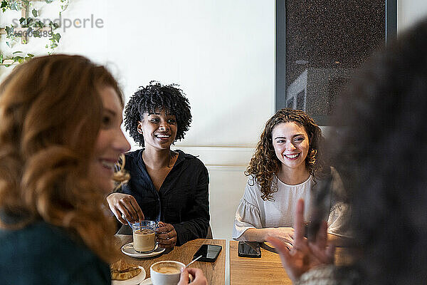 Glückliche junge Frau  die mit Freunden im Café genießt