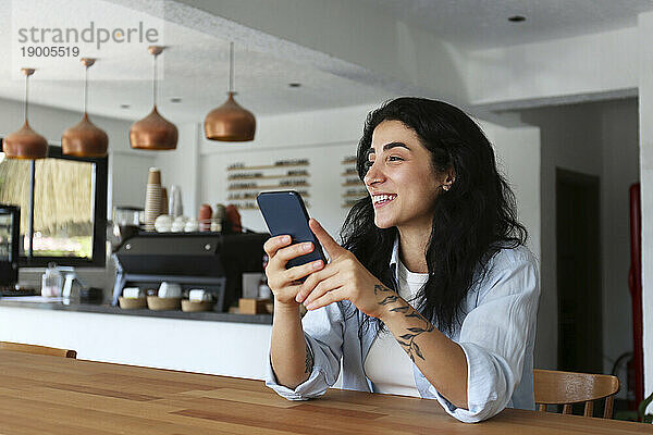 Lächelnde Frau hält Smartphone im Café